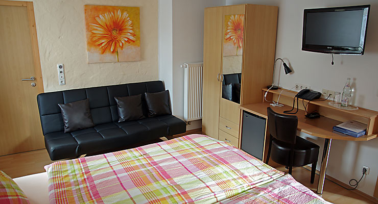 Gemütliches Gästezimmer mit Doppelbett, Sofa und Sitzgelegenheit Gästezimmer mit Couch und Schreibtisch im Gästehaus Kloep in Hillesheim